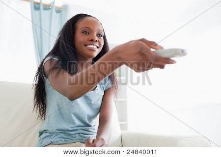 Mulher sorridente no sofá mudando de programa de TV