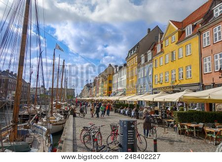 Copenhagen, Denmark - May 15, 2017: People Stroll Near Restaurants And Pubs Along The Cobblestone St