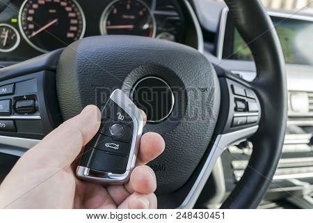 Man's Hand Holding A Wireless  Car Key In Black Leather Interior. Modern Car Interior Details. Car D
