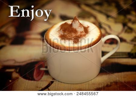 Cup Of Coffee With Cinnamon And The Word Enjoy On A Table