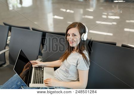 Young Smiling Traveler Tourist Woman With Headphones Listen Music Working On Laptop With Blank Scree