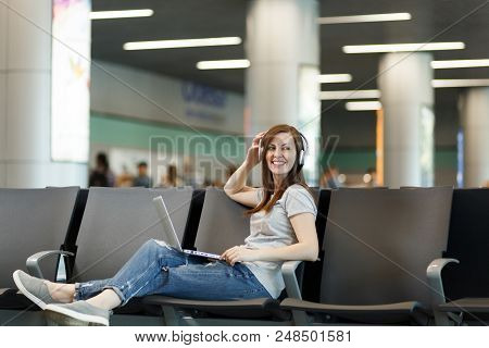 Young Attractive Traveler Tourist Woman With Headphones Listen Music, Working On Laptop, Wait In Lob
