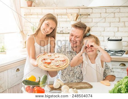 dad with two little daughters preparing pizza in the kitchen