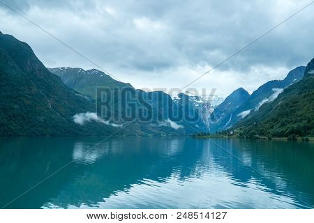 Briksdal Glacier Behind Mountain Lake With Reflection In Briksdalbreen