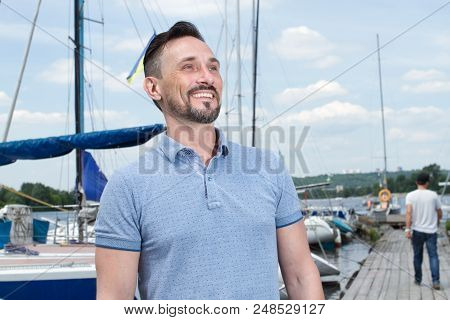 Young Cheerful Bearded Man Relaxing On Sailboat Posing And Looking At Far On Background Of Boats, Sk