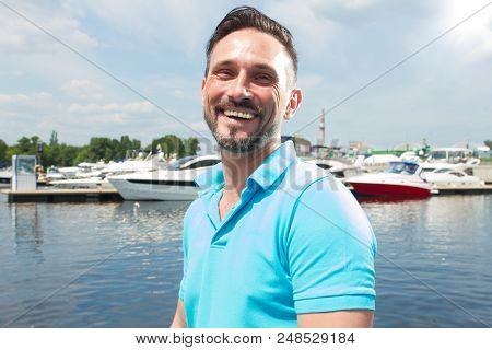 Portrait Of Smiling Happy Yachtsman On Marina With Boat Background. Summer Vacation Yachting Time Fo