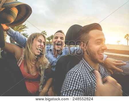 Happy Millenial Friends Having Fun In Convertible Car At Sunset - Young People Driving And Laughing 