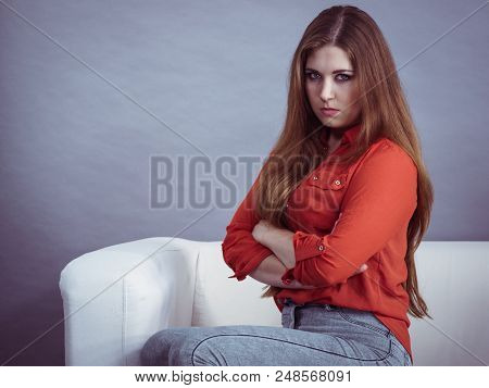 Angry, Pissed Off Young Woman. Attractive Female With Long Brown Hair Sitting On Sofa Being Mad And 