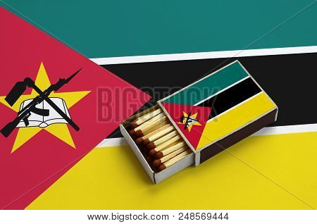 Mozambique Flag  Is Shown In An Open Matchbox, Which Is Filled With Matches And Lies On A Large Flag