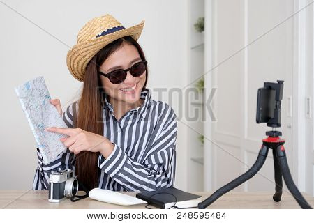 Portrait Of Young Asian Woman Travel Blogger Holding Map While Recording Video, Live Streaming, On S