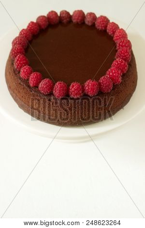 Chocolate Brownie Cake With Raspberries And Chocolate Icing On A Light Background. Selective Focus.