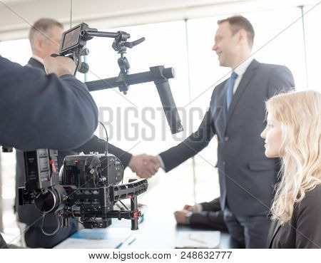 Videographer Using Steadycam, Making Video Of Business People Shaking Hands