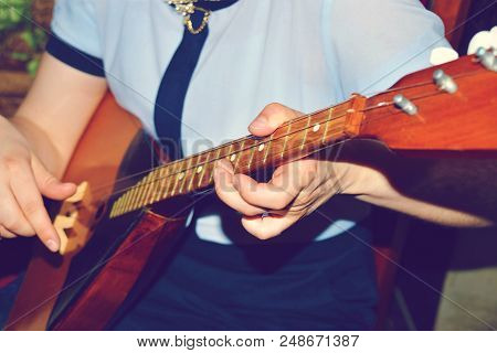 The Boy Plays The Guitar And Takes Chords, Dombra On The Background Of The Piano.