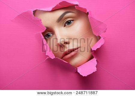 Pretty Girl's Face In The Hole Of Lacerated Pink Cardboard.