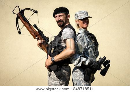 The Smiling Male And Female Soldiers In Military Uniform Is Posing With Crossbow Weapon And Binocula