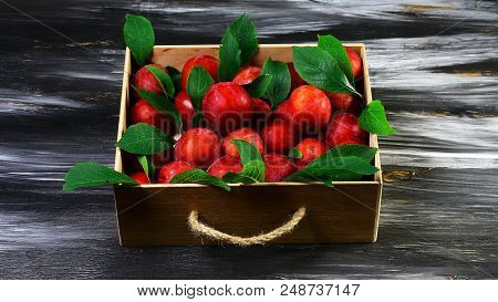 Ripe Delicious Red Plums In Wooden Box On Dark Background. Top View, Space For Text.