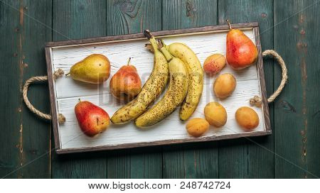 Fresh Fruit On A White Wooden Tray: Banatas, Pears, Apricots. Countryside Setting. Top View. Copy Sp