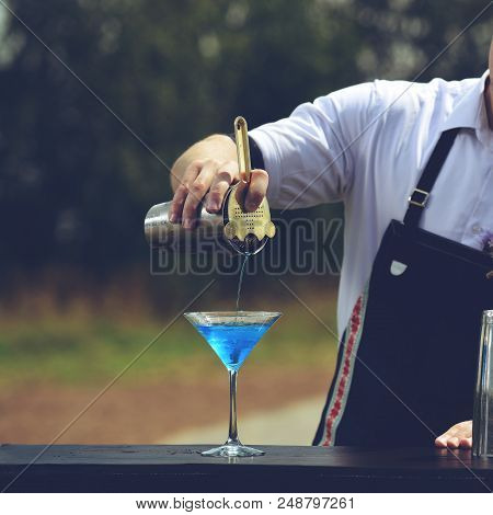 Bartender Workplace. Bartender On The Street Catering Bar Preparing A Coctail In A Martini Glass, Se