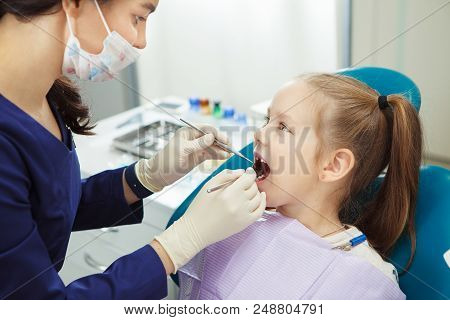 Child Lies In Comfortable Dentis Chair And Goes Through Procedure Without Fear While Female Doctor I