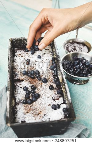 Berry Crumble In The Baking-tin And Small Bowl With Blueberries On The Blue Wooden Table. Woman Spri