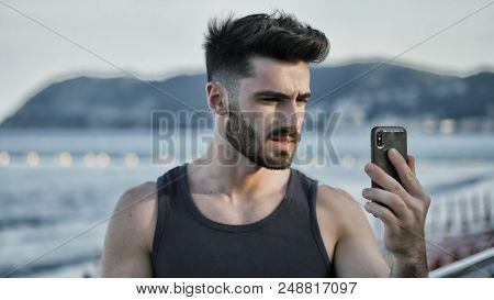 Young Man At Beach Taking Selfie Photo With His Cell Phone