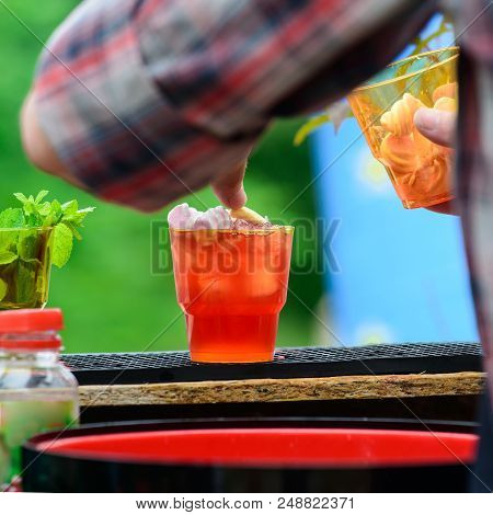 Selective Focus On Cold Fresh Cocktails In Glasses With Straw On Wooden Board. Process Of Preparing 