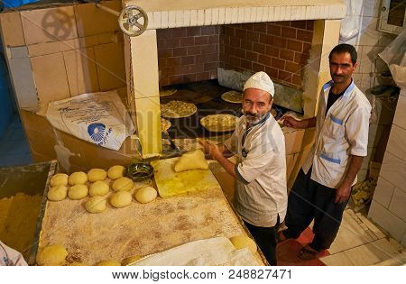 Kerman, Iran - October 16, 2017: The Portrait Of The Bakers At Work, Standing At The Large Oven With
