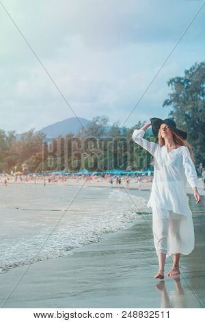 Handsome Girl In Hat On The Beach Background. Portrait Of A Woman In White Clothes And Balck Hat On 