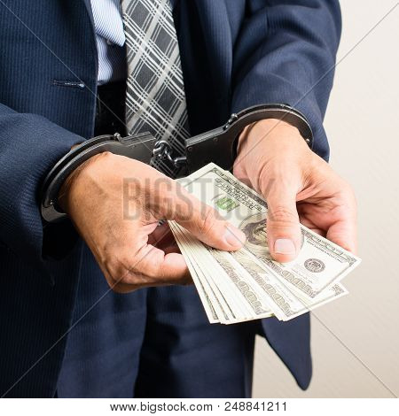 Arrested Official In Handcuffs Counting Dollar Banknotes. Concept Of Fraud, Detention, Crime And Bri