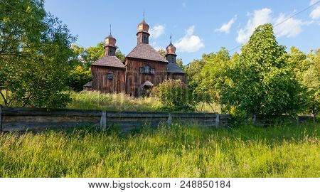 An Old Wooden Church With Three Shining Domes Overgrown With Tall Grass. As In The Film Viy