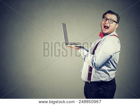 Side View Of Overweight Business Man In Glasses Holding Laptop Computer And Looking Shocked And Amaz