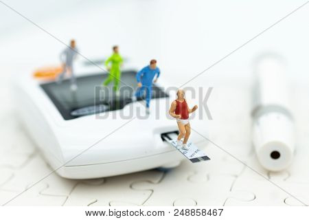 Miniature People Exercise Running On Glucose Meter With Lancet. Image Use For Medicine, Diabetes, He