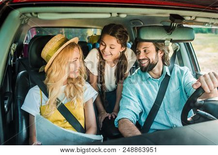 Smiling Parents And Daughter Traveling By Car With Map