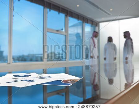 Saudi Arab Businessmen Talking In A Meeting Room, Focus On Ducuments On The Table