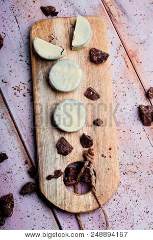 high angle view of some argentinean-uruguayan alfajores filled with dulce de leche and coated with a white coating on a wooden chopping board, on a rustic table