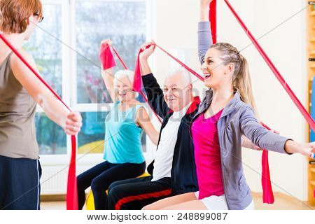 Senior people at fitness course in gym exercising with stretch band