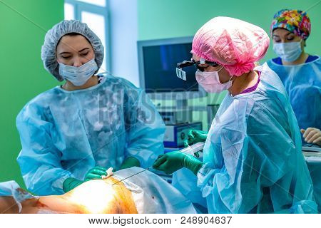 Cosmetic Liposuction Surgery In Actual Operating Room Setting Showing Surgeon Hands And Cannula
