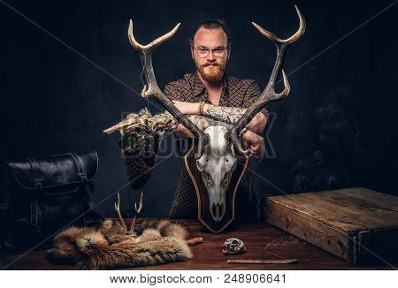 Redhead Taxidermist Hipster Male In Sunglasses Dressed In A Brown Shirt, Standing Near A Table With 
