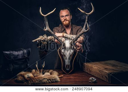 Redhead Taxidermist Hipster Male In Sunglasses Dressed In A Brown Shirt, Standing Near A Table With 