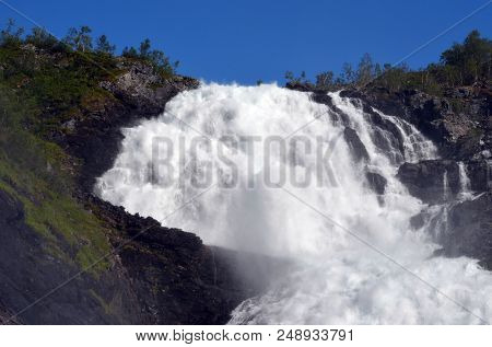 Kjosfossen waterfall flows down valley by the station on the train between Flam and Myrdal in Norway
