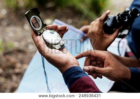 Trekking couple using map and compass in a forest