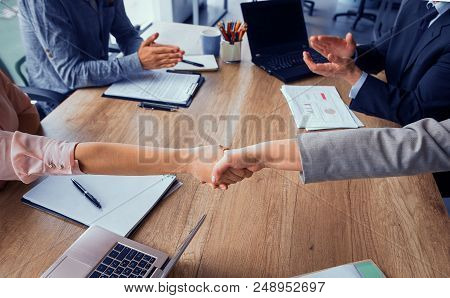 Business Agreement, Handshake Of Partners After Concluding A Deal. Two Business Teams Sitting At Bot