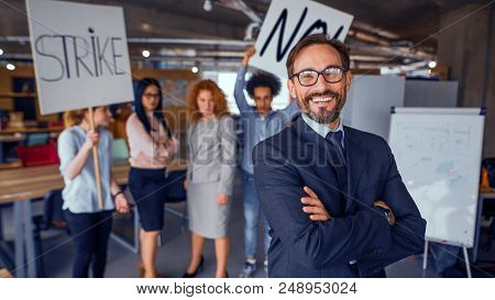 Modern Office Concept, Director Standing With His Back To Striking Cowokers. Unhappy Employees Holdi