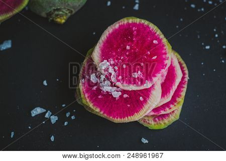 Watermelon Radishes Sliced, Sprinkled With Sea Salt On A Black Background
