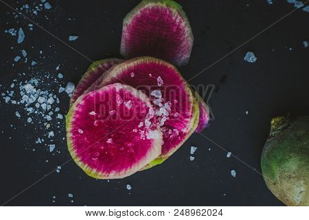 Watermelon Radishes Sliced, Sprinkled With Sea Salt On A Black Background
