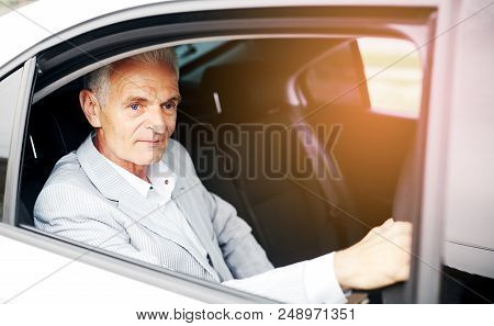 Old Bussines Man Sitting In The Car And Look Around. Thinking About New Possibilities.