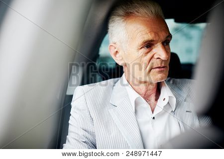 Old Bussines Man Sitting In The Car And Look Around. Thinking About New Possibilities.