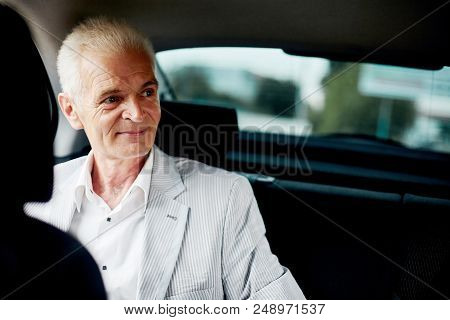 Old Bussines Man Sitting In The Car And Look Around And Smilling. Thinking About New Possibilities.