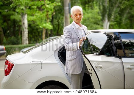 Old Gray-haired Bussines Man In Formalwear Coming Out Of The Car