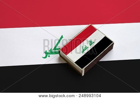 Iraq Flag  Is Pictured On A Matchbox That Lies On A Large Flag.